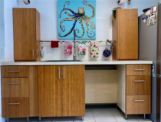 232 Darst Ave, Punta Gorda, FL 33950 - kitchen featuring freestanding refrigerator, brown cabinets, light tile patterned floors, and light countertops