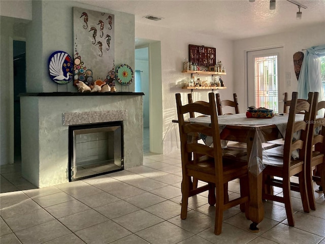 232 Darst Ave, Punta Gorda, FL 33950 - dining room with tile patterned flooring, a glass covered fireplace, rail lighting, and a textured ceiling
