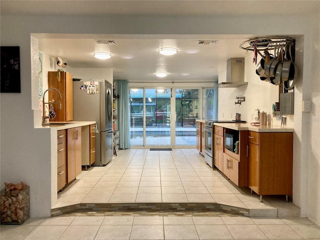 232 Darst Ave, Punta Gorda, FL 33950 - kitchen with wall chimney exhaust hood, light tile patterned floors, stainless steel appliances, brown cabinetry, and light countertops