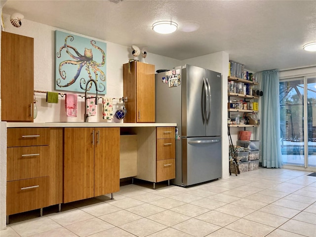232 Darst Ave, Punta Gorda, FL 33950 - kitchen with freestanding refrigerator, brown cabinets, light tile patterned floors, a textured ceiling, and light countertops