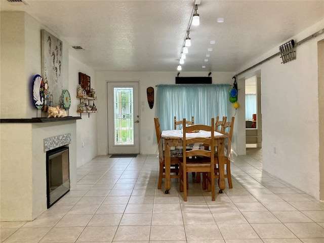 232 Darst Ave, Punta Gorda, FL 33950 - dining room featuring rail lighting, light tile patterned floors, a tiled fireplace, and a textured ceiling