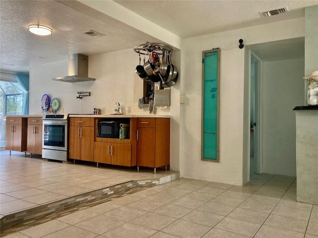232 Darst Ave, Punta Gorda, FL 33950 - kitchen featuring wall chimney range hood, black microwave, a textured ceiling, light tile patterned floors, and brown cabinetry