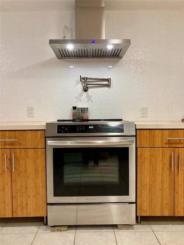232 Darst Ave, Punta Gorda, FL 33950 - kitchen with stainless steel range with electric cooktop, wall chimney exhaust hood, light countertops, brown cabinetry, and a textured wall