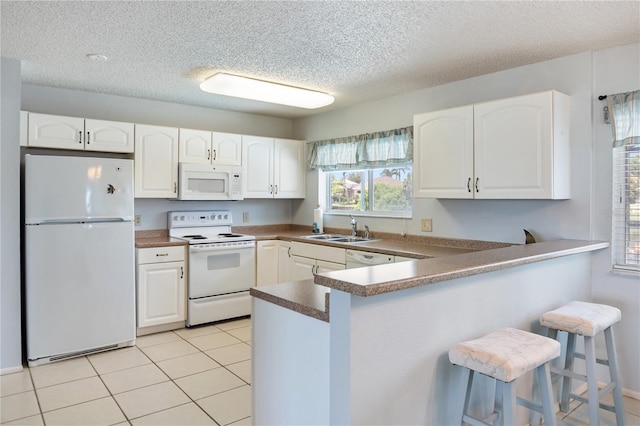 17103 Horizon Ln, Port Charlotte, FL 33948 - kitchen featuring white appliances, a peninsula, a kitchen breakfast bar, white cabinetry, and a textured ceiling