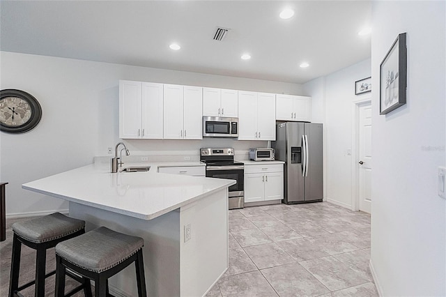 8516 Cache Dr, Sarasota, FL 34240 - kitchen with appliances with stainless steel finishes, a breakfast bar area, a peninsula, white cabinetry, and light countertops