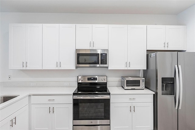8516 Cache Dr, Sarasota, FL 34240 - kitchen with stainless steel appliances, white cabinetry, and light countertops