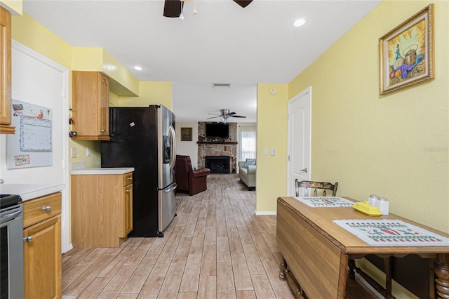 22559 Adorn Ave, Port Charlotte, FL 33952 - kitchen featuring ceiling fan, stainless steel refrigerator with ice dispenser, a fireplace, light wood-type flooring, and light countertops