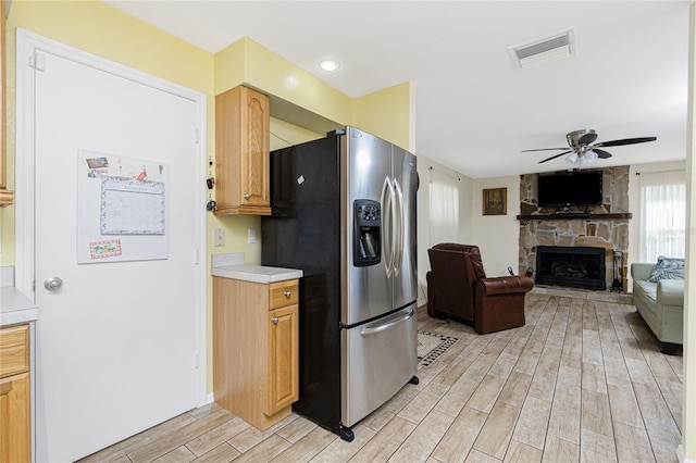 22559 Adorn Ave, Port Charlotte, FL 33952 - kitchen with stainless steel fridge with ice dispenser, light wood-type flooring, light countertops, a ceiling fan, and a fireplace