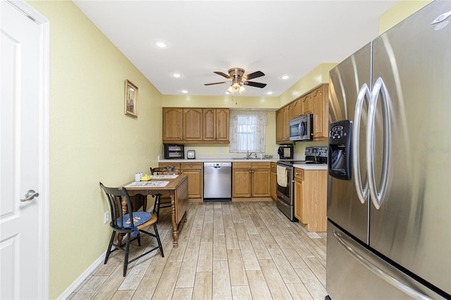 22559 Adorn Ave, Port Charlotte, FL 33952 - kitchen with appliances with stainless steel finishes, light countertops, light wood-style floors, a ceiling fan, and brown cabinetry