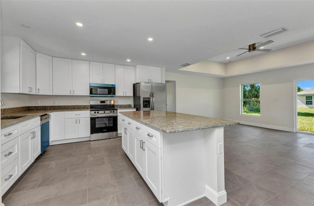 3435 W Price Blvd, North Port, FL 34286 - kitchen featuring stainless steel appliances, light stone counters, white cabinets, ceiling fan, and a kitchen island