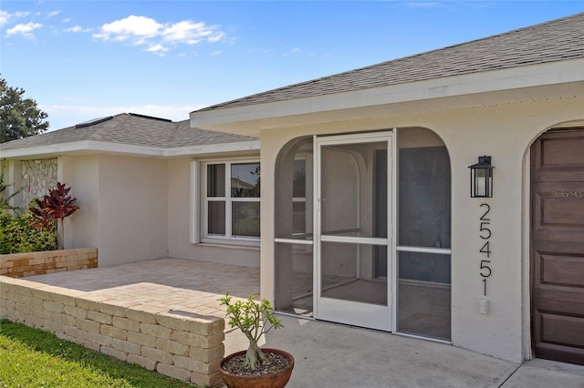 25451 Kowloon Ln, Punta Gorda, FL 33983 - back of property with a shingled roof, a patio, stucco siding, and a sunroom