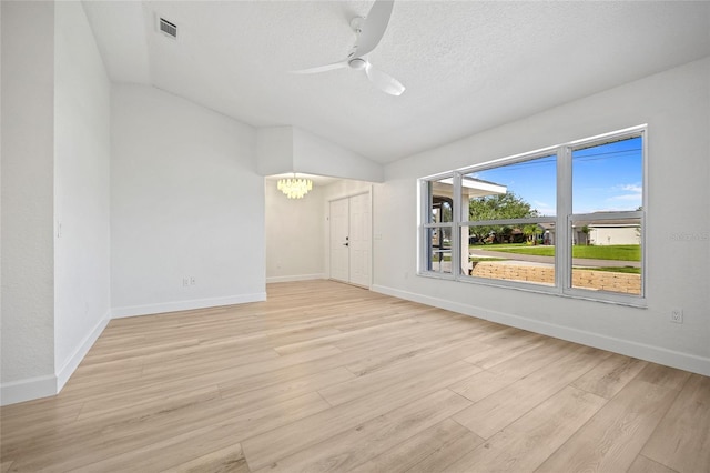 25451 Kowloon Ln, Punta Gorda, FL 33983 - empty room with vaulted ceiling, a ceiling fan, a chandelier, light wood-style flooring, and a textured ceiling