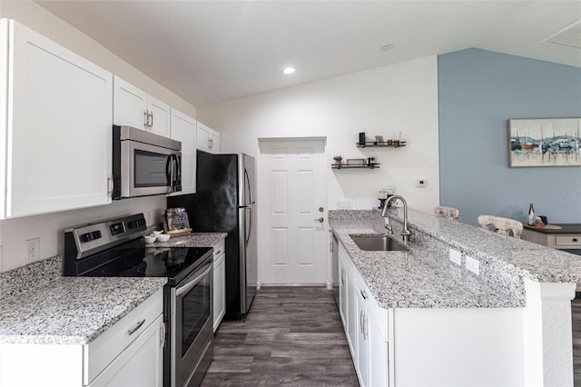 1710 Blackwood Cir, North Port, FL 34288 - kitchen with stainless steel appliances, a peninsula, lofted ceiling, dark wood-style floors, and white cabinets