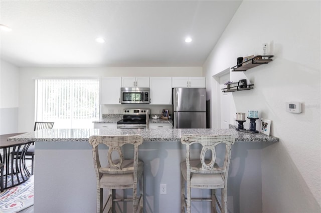 1710 Blackwood Cir, North Port, FL 34288 - kitchen with stainless steel appliances, light stone countertops, a peninsula, white cabinetry, and a breakfast bar area