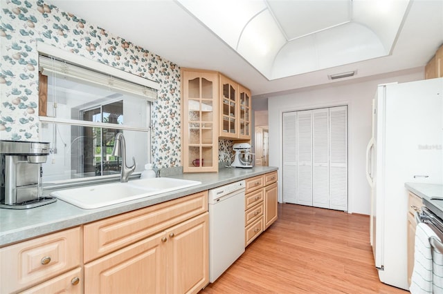 3425 Magnolia Way, Punta Gorda, FL 33950 - kitchen featuring white appliances, a tray ceiling, light wood-style flooring, light brown cabinetry, and glass insert cabinets