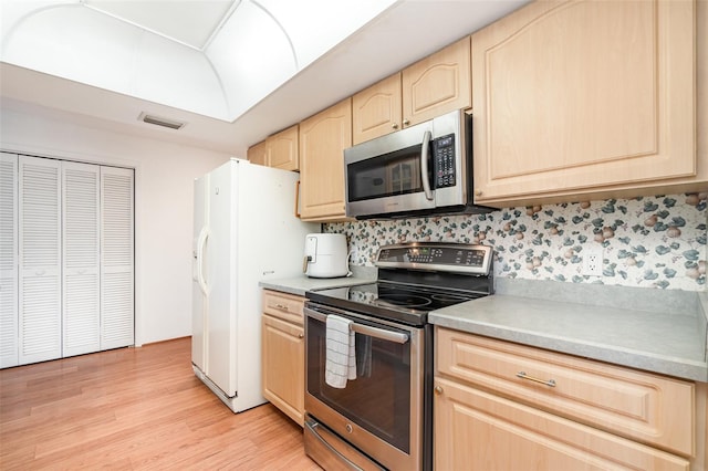 3425 Magnolia Way, Punta Gorda, FL 33950 - kitchen featuring stainless steel appliances, light brown cabinetry, light wood-type flooring, tasteful backsplash, and light countertops