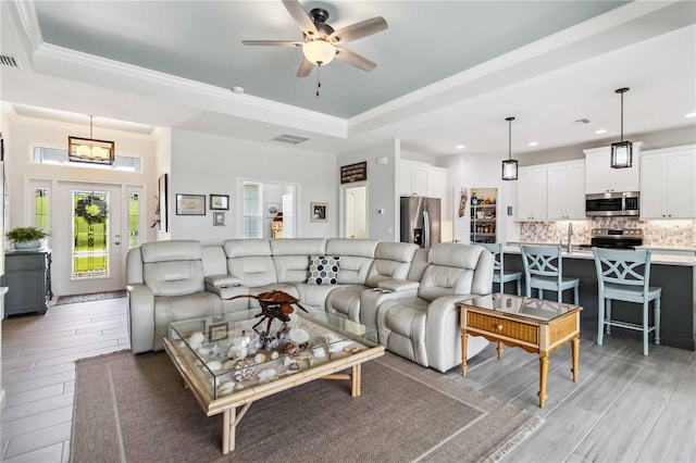 13416 Trascoro Ln, Port Charlotte, FL 33981 - living room featuring a tray ceiling, light wood-style flooring, recessed lighting, ceiling fan, and ornamental molding