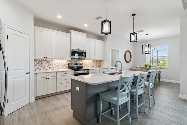 13416 Trascoro Ln, Port Charlotte, FL 33981 - kitchen featuring appliances with stainless steel finishes, backsplash, an island with sink, a kitchen bar, and white cabinets