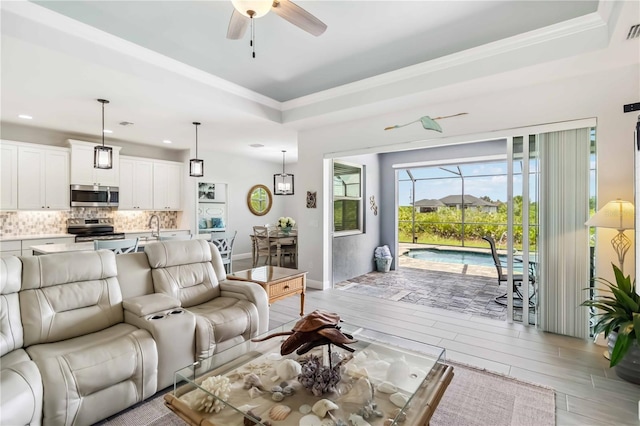 13416 Trascoro Ln, Port Charlotte, FL 33981 - living room featuring crown molding, a ceiling fan, light wood finished floors, a raised ceiling, and recessed lighting