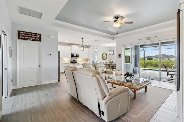 13416 Trascoro Ln, Port Charlotte, FL 33981 - living room featuring a ceiling fan, recessed lighting, a tray ceiling, and light wood-style flooring