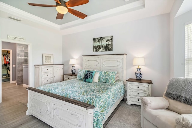 13416 Trascoro Ln, Port Charlotte, FL 33981 - bedroom with a tray ceiling, a walk in closet, a closet, light wood-type flooring, and ornamental molding