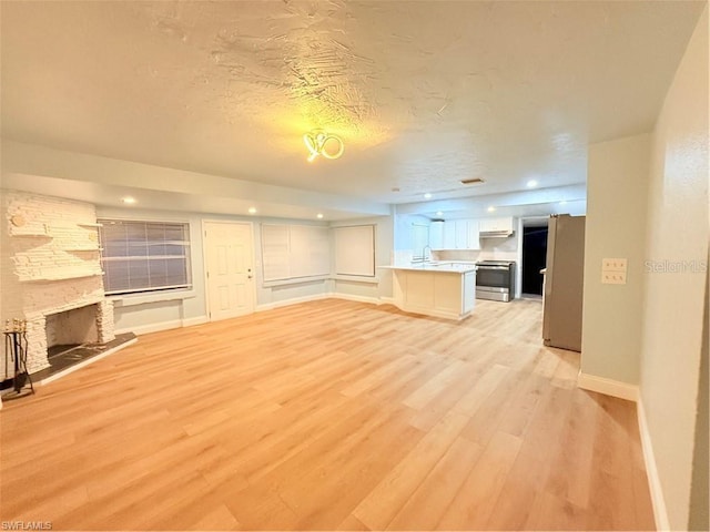 3902 Locust Ave, Sarasota, FL 34234 - unfurnished living room with light wood-style flooring, a fireplace, a textured ceiling, and recessed lighting