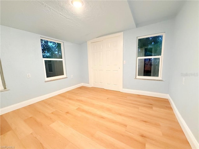 3902 Locust Ave, Sarasota, FL 34234 - unfurnished bedroom with light wood-style floors, a textured ceiling, vaulted ceiling, and a closet