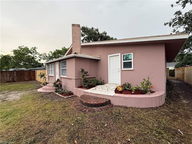 3902 Locust Ave, Sarasota, FL 34234 - back of house with a fenced backyard, stucco siding, and a chimney