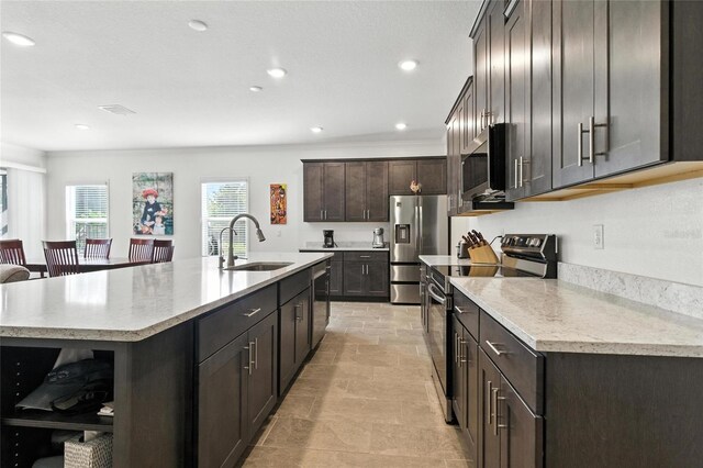 2456 Nabble Ln, North Port, FL 34288 - kitchen with stainless steel appliances, open shelves, a kitchen island with sink, dark brown cabinetry, and recessed lighting