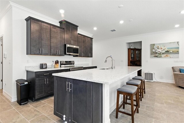 2456 Nabble Ln, North Port, FL 34288 - kitchen with appliances with stainless steel finishes, ornamental molding, a kitchen breakfast bar, recessed lighting, and an island with sink