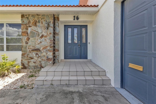 16 Tropicana Dr, Punta Gorda, FL 33950 - doorway to property featuring stucco siding, a tile roof, stone siding, and a garage