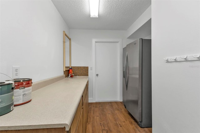 16 Tropicana Dr, Punta Gorda, FL 33950 - kitchen featuring stainless steel refrigerator with ice dispenser, wood finished floors, a textured ceiling, light countertops, and brown cabinets