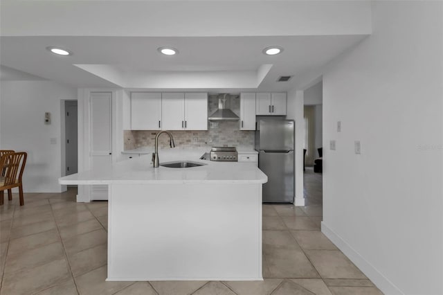16 Tropicana Dr, Punta Gorda, FL 33950 - kitchen featuring freestanding refrigerator, wall chimney range hood, a tray ceiling, light countertops, and tasteful backsplash