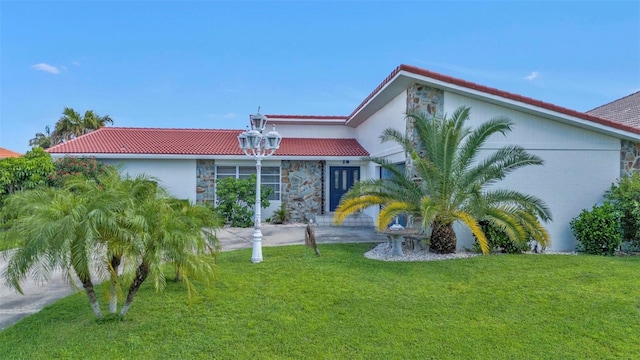 16 Tropicana Dr, Punta Gorda, FL 33950 - mediterranean / spanish-style home with a front lawn, a tile roof, stone siding, and stucco siding