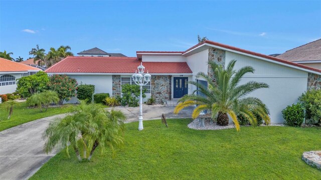 16 Tropicana Dr, Punta Gorda, FL 33950 - mediterranean / spanish home with stone siding, a tile roof, a front lawn, and stucco siding