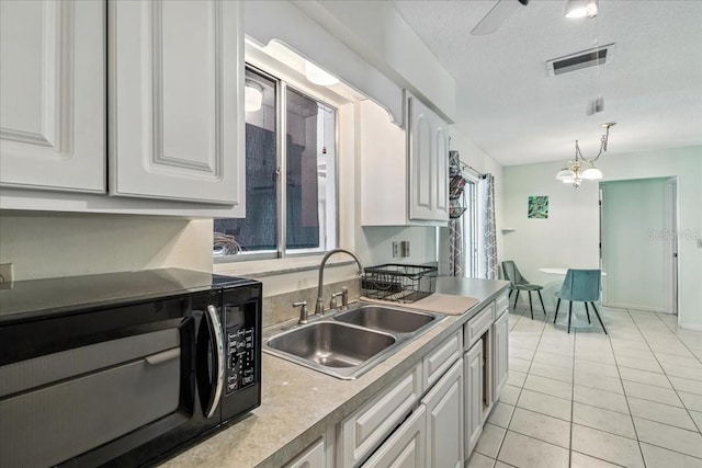740 Dobell Ter NW, Port Charlotte, FL 33948 - kitchen featuring black microwave, white cabinets, decorative light fixtures, light tile patterned flooring, and a textured ceiling