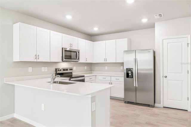2047 Royal Tern Cir, Punta Gorda, FL 33983 - kitchen featuring stainless steel appliances, a peninsula, light countertops, light wood finished floors, and white cabinets