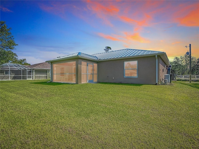 5493 Jody Ave, North Port, FL 34288 - back of property at dusk with stucco siding, a lawn, a metal roof, and a standing seam roof