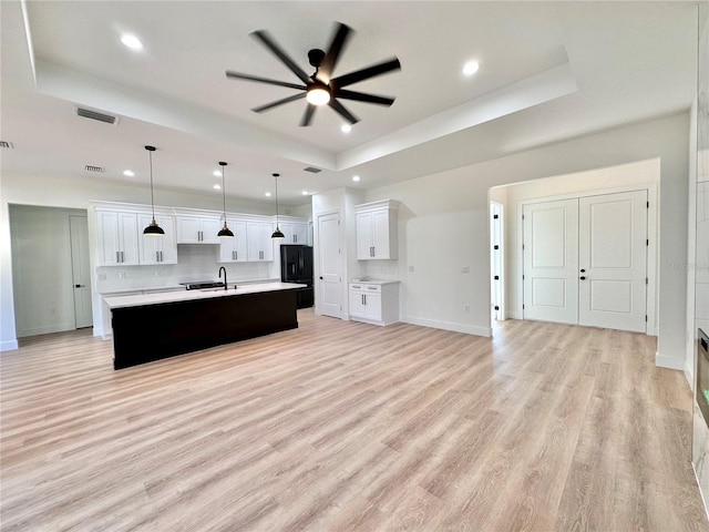 4748 Sylvania Ave, North Port, FL 34286 - kitchen with a raised ceiling, black refrigerator, a ceiling fan, a spacious island, and light countertops