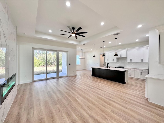 4748 Sylvania Ave, North Port, FL 34286 - kitchen with a raised ceiling, open floor plan, light countertops, ceiling fan, and light wood-style floors