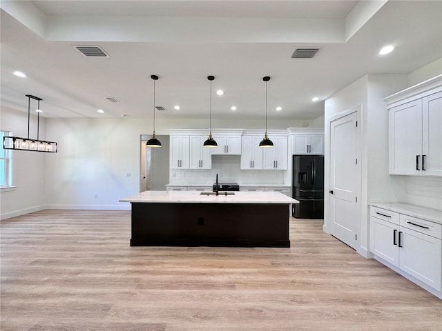 4748 Sylvania Ave, North Port, FL 34286 - kitchen with black fridge with ice dispenser, light wood-style flooring, tasteful backsplash, a large island, and white cabinetry