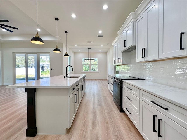 4748 Sylvania Ave, North Port, FL 34286 - kitchen with black electric range oven, light wood-style floors, ceiling fan, tasteful backsplash, and a center island with sink