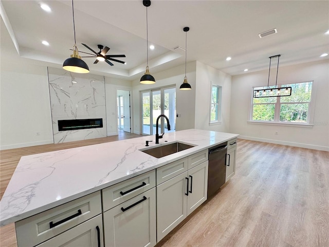 4748 Sylvania Ave, North Port, FL 34286 - kitchen with open floor plan, dishwashing machine, a raised ceiling, light wood-style floors, and a premium fireplace