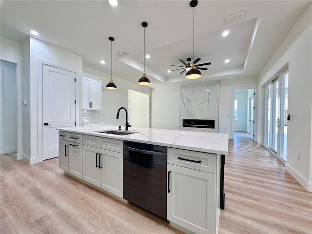 4748 Sylvania Ave, North Port, FL 34286 - kitchen with black dishwasher, a raised ceiling, light wood finished floors, ceiling fan, and a center island with sink