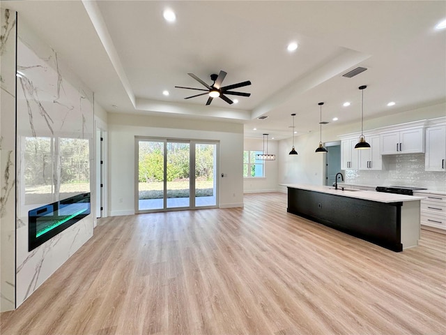 4748 Sylvania Ave, North Port, FL 34286 - kitchen with a tray ceiling, open floor plan, light countertops, a ceiling fan, and light wood-type flooring