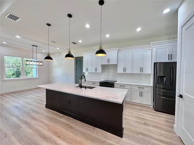 4748 Sylvania Ave, North Port, FL 34286 - kitchen with fridge with ice dispenser, tasteful backsplash, white cabinetry, light stone countertops, and an island with sink