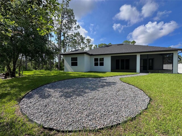 4748 Sylvania Ave, North Port, FL 34286 - rear view of house featuring a lawn, driveway, a sunroom, and stucco siding