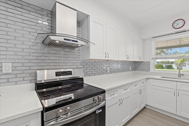 315 Durrance St, Punta Gorda, FL 33950 - kitchen with stainless steel electric stove, wall chimney exhaust hood, decorative backsplash, and white cabinets
