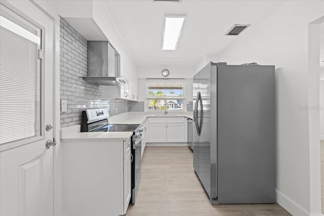 315 Durrance St, Punta Gorda, FL 33950 - kitchen featuring stainless steel appliances, wall chimney range hood, light countertops, light wood-style floors, and tasteful backsplash