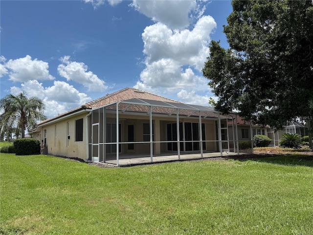 2760 Royal Palm Dr, North Port, FL 34288 - rear view of house with stucco siding, a lawn, glass enclosure, a tiled roof, and a patio area